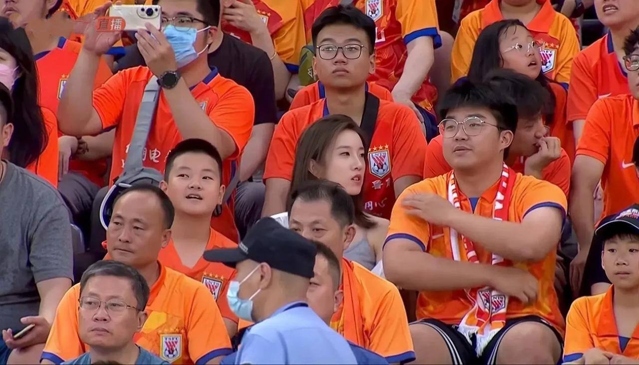 山东泰山对阵上海申花的比赛中，看台上的一个美女球迷和她男朋友。
这个美女长发飘飘